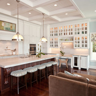 Traditional open concept kitchen remodeling - Example of a classic l-shaped open concept kitchen design in Tampa with glass-front cabinets, white cabinets and white backsplash