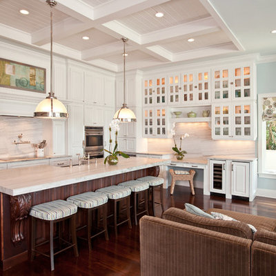 Example of a classic l-shaped open concept kitchen design in Tampa with glass-front cabinets, white cabinets and white backsplash