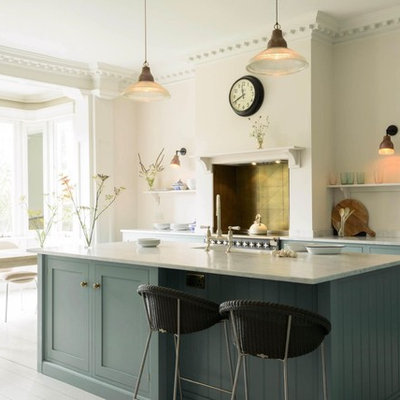 Example of a transitional galley painted wood floor eat-in kitchen design in Hertfordshire with a farmhouse sink, shaker cabinets, blue cabinets, marble countertops, metal backsplash, stainless steel appliances, an island and gray countertops