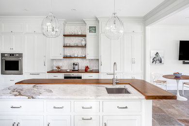 Eat-in kitchen - transitional eat-in kitchen idea in New York with an undermount sink, shaker cabinets, white cabinets, wood countertops, stainless steel appliances, an island and brown countertops