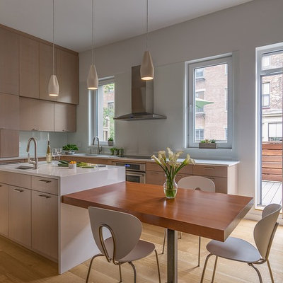 Inspiration for a mid-sized contemporary l-shaped medium tone wood floor and brown floor eat-in kitchen remodel in Boston with an undermount sink, flat-panel cabinets, light wood cabinets, quartz countertops, white backsplash, glass sheet backsplash, stainless steel appliances, an island and white countertops
