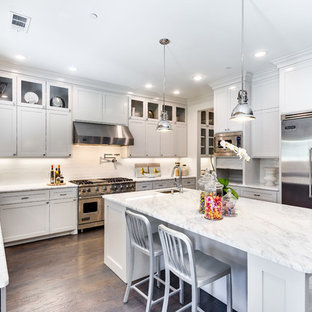Example of a transitional dark wood floor kitchen design in Dallas with a farmhouse sink, shaker cabinets, white cabinets, marble countertops, white backsplash, porcelain backsplash and stainless steel appliances