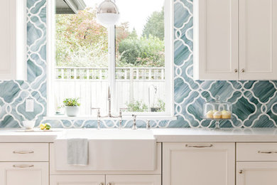 Inspiration for a mid-sized transitional u-shaped light wood floor kitchen remodel in Portland with a farmhouse sink, recessed-panel cabinets, white cabinets, quartz countertops, green backsplash, mosaic tile backsplash and paneled appliances