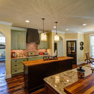 Design ideas for a large country l-shaped eat-in kitchen in Other with a farmhouse sink, beaded inset cabinets, green cabinets, wood benchtops, red splashback, brick splashback, stainless steel appliances, medium hardwood floors, multiple islands and brown floor.