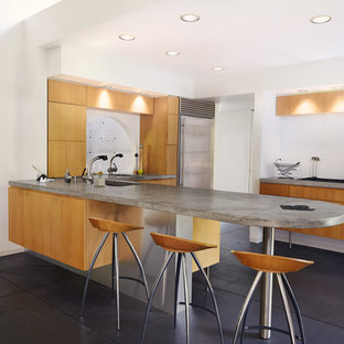 Foto di una cucina minimalista di medie dimensioni con lavello sottopiano, ante lisce, ante in legno scuro, top in cemento, elettrodomestici in acciaio inossidabile, pavimento in cemento e pavimento nero