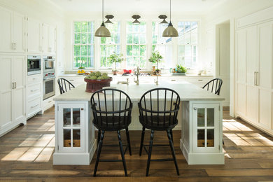 Foto de cocina de estilo de casa de campo grande con puertas de armario blancas, una isla, encimera de piedra caliza, armarios con paneles empotrados, salpicadero blanco, electrodomésticos con paneles y suelo de madera oscura