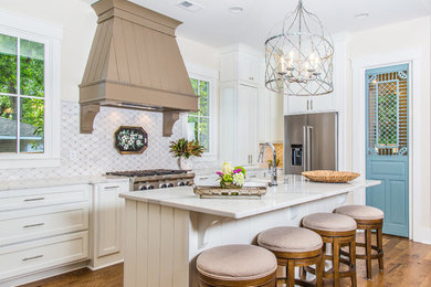 Example of a mid-sized cottage chic l-shaped medium tone wood floor kitchen design in Other with an undermount sink, recessed-panel cabinets, white cabinets, marble countertops, stainless steel appliances, an island and white backsplash