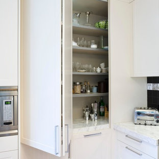 Photo of a mid-sized contemporary u-shaped kitchen in Other with an undermount sink, white cabinets, marble benchtops, black splashback, ceramic splashback, stainless steel appliances, light hardwood floors and no island.