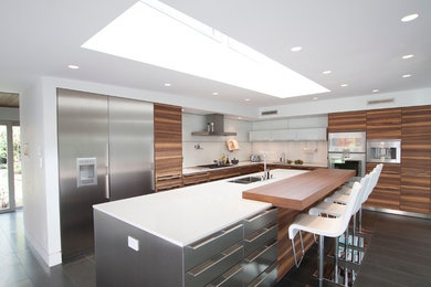Eat-in kitchen - modern l-shaped eat-in kitchen idea in Vancouver with an undermount sink, flat-panel cabinets, medium tone wood cabinets, glass tile backsplash, stainless steel appliances and an island