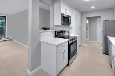 Example of a mid-sized danish galley vinyl floor and gray floor kitchen pantry design in Vancouver with a double-bowl sink, flat-panel cabinets, white cabinets, quartzite countertops, white backsplash, ceramic backsplash, stainless steel appliances and white countertops