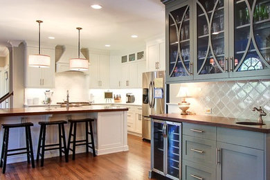 Kitchen - transitional kitchen idea in Charlotte with glass-front cabinets, wood countertops and an island