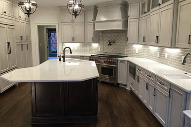 Example of a transitional dark wood floor kitchen design in Charlotte with an undermount sink, shaker cabinets, gray cabinets, quartz countertops, gray backsplash, ceramic backsplash and paneled appliances