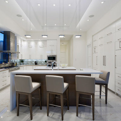 Large trendy u-shaped porcelain tile and white floor eat-in kitchen photo in Miami with flat-panel cabinets, white cabinets, quartz countertops, beige backsplash, glass tile backsplash, white appliances, two islands and white countertops