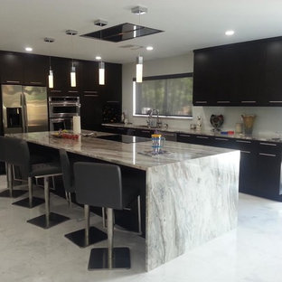 Photo of a medium sized contemporary l-shaped kitchen/diner in Miami with a submerged sink, flat-panel cabinets, black cabinets, granite worktops, stainless steel appliances, ceramic flooring, an island and grey floors.