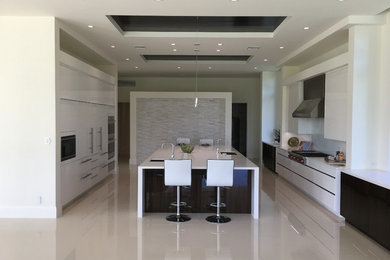 Kitchen - large contemporary kitchen idea in Miami with flat-panel cabinets, white cabinets, black appliances and an island