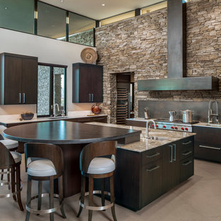Imagen de cocina en U, actual, grande, con fregadero bajoencimera, armarios con paneles lisos, puertas de armario de madera en tonos medios, encimera de cuarcita, salpicadero negro, electrodomésticos de acero inoxidable, suelo de baldosas de porcelana, una isla, suelo beige y encimeras beige
