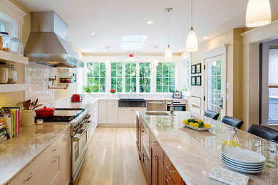 Design ideas for a large traditional l-shaped kitchen in Boston with recessed-panel cabinets, white cabinets, engineered stone countertops, white splashback, metro tiled splashback, stainless steel appliances, light hardwood flooring and an island.