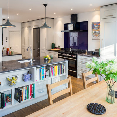 Transitional medium tone wood floor and brown floor eat-in kitchen photo in London with an undermount sink, shaker cabinets, gray cabinets, glass sheet backsplash, black appliances, an island and gray countertops
