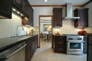 Example of a large transitional l-shaped eat-in kitchen design in Columbus with an undermount sink, raised-panel cabinets, dark wood cabinets, granite countertops, gray backsplash, ceramic backsplash, stainless steel appliances and an island