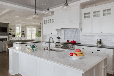 Design ideas for a large classic u-shaped open plan kitchen in Portland Maine with a submerged sink, shaker cabinets, white cabinets, marble worktops, white splashback, metro tiled splashback, stainless steel appliances, medium hardwood flooring and an island.