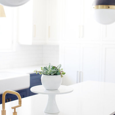 Eat-in kitchen - mid-sized farmhouse galley dark wood floor and brown floor eat-in kitchen idea in Los Angeles with a farmhouse sink, shaker cabinets, white cabinets, quartzite countertops, white backsplash, subway tile backsplash, stainless steel appliances and an island