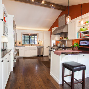 Mediterranean eat-in kitchen photos - Eat-in kitchen - mediterranean galley medium tone wood floor and brown floor eat-in kitchen idea in Seattle with a farmhouse sink, white cabinets, granite countertops, beige backsplash, stainless steel appliances, shaker cabinets, a peninsula and wood backsplash
