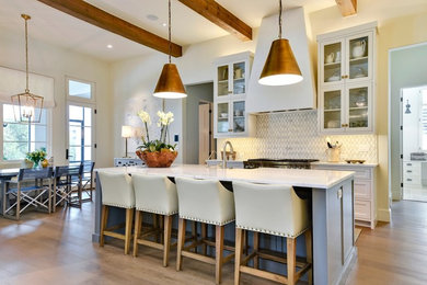 Kitchen - transitional galley medium tone wood floor and brown floor kitchen idea in Austin with a farmhouse sink, shaker cabinets, gray cabinets, white backsplash, mosaic tile backsplash, stainless steel appliances, an island and white countertops