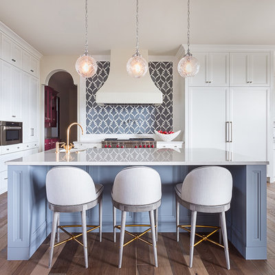 Example of a mid-sized transitional l-shaped medium tone wood floor and brown floor kitchen pantry design in Austin with an undermount sink, shaker cabinets, white cabinets, marble countertops, gray backsplash, stone tile backsplash, paneled appliances and an island