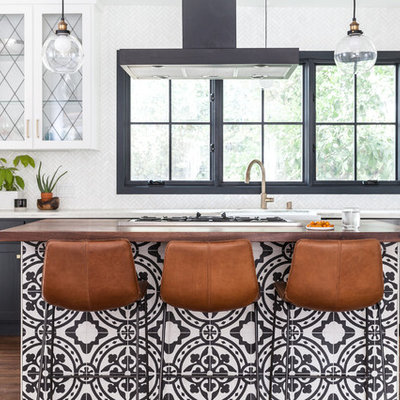 Tuscan galley medium tone wood floor and brown floor kitchen photo in Sacramento with a farmhouse sink, glass-front cabinets, white cabinets, marble countertops, white backsplash, marble backsplash, an island, white countertops and stainless steel appliances