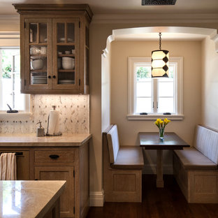 This is an example of a mid-sized mediterranean u-shaped eat-in kitchen in Santa Barbara with an integrated sink, beige cabinets, quartzite benchtops, white splashback, mosaic tile splashback, stainless steel appliances, medium hardwood floors, with island and glass-front cabinets.