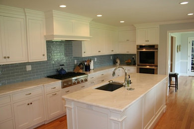 Exempel på ett mellanstort klassiskt l-kök, med en undermonterad diskho, skåp i shakerstil, vita skåp, marmorbänkskiva, blått stänkskydd, stänkskydd i tunnelbanekakel, rostfria vitvaror, mellanmörkt trägolv, brunt golv och en köksö