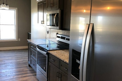Mittelgroße Klassische Küche mit Unterbauwaschbecken, Schrankfronten im Shaker-Stil, dunklen Holzschränken, Granit-Arbeitsplatte und Küchenrückwand in Weiß in Kansas City
