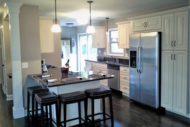 Mid-sized elegant l-shaped dark wood floor eat-in kitchen photo in Chicago with an undermount sink, raised-panel cabinets, white cabinets, granite countertops, stainless steel appliances and an island