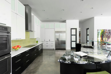 Inspiration for a huge modern concrete floor kitchen remodel in Dallas with an undermount sink, flat-panel cabinets, black cabinets, granite countertops, green backsplash, mosaic tile backsplash, stainless steel appliances and an island