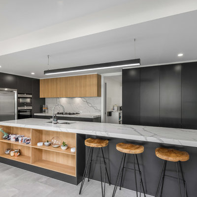 Large trendy galley porcelain tile and gray floor open concept kitchen photo in Brisbane with flat-panel cabinets, gray cabinets, an island, an undermount sink, quartz countertops, white backsplash, stone slab backsplash and stainless steel appliances