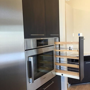 This is an example of an expansive midcentury l-shaped eat-in kitchen in Other with an undermount sink, flat-panel cabinets, dark wood cabinets, marble benchtops, beige splashback, porcelain splashback, stainless steel appliances, medium hardwood floors, with island and brown floor.