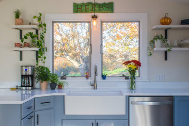 Eat-in kitchen - mid-sized farmhouse u-shaped beige floor eat-in kitchen idea in Providence with a farmhouse sink, shaker cabinets, blue cabinets, quartz countertops, white backsplash, stainless steel appliances, an island and white countertops