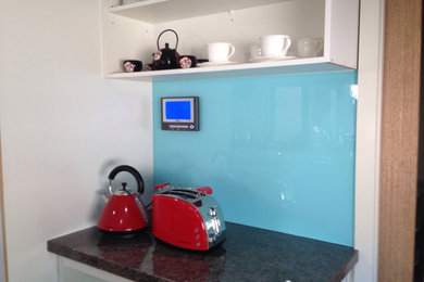 Cette image montre une cuisine design avec une crédence bleue.