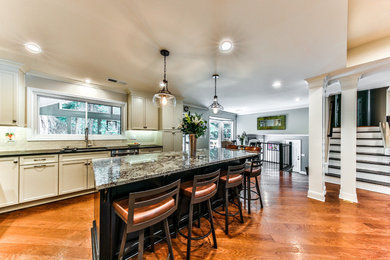 Open concept kitchen - large transitional l-shaped medium tone wood floor open concept kitchen idea in Atlanta with shaker cabinets, white cabinets, granite countertops, white backsplash, an island, an undermount sink, subway tile backsplash and stainless steel appliances