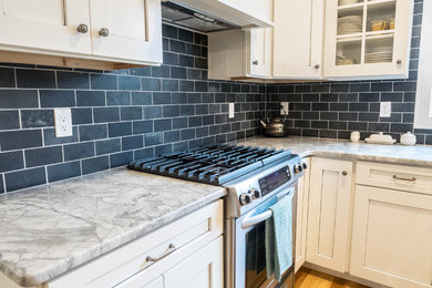 Kitchen - mid-sized transitional medium tone wood floor kitchen idea in New York with shaker cabinets, white cabinets, marble countertops, blue backsplash, subway tile backsplash and stainless steel appliances