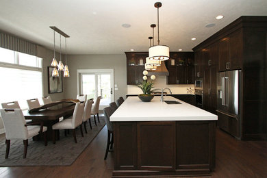 Mid-sized transitional l-shaped dark wood floor and brown floor eat-in kitchen photo in Omaha with an undermount sink, recessed-panel cabinets, dark wood cabinets, quartz countertops, white backsplash, stone slab backsplash, stainless steel appliances, an island and white countertops