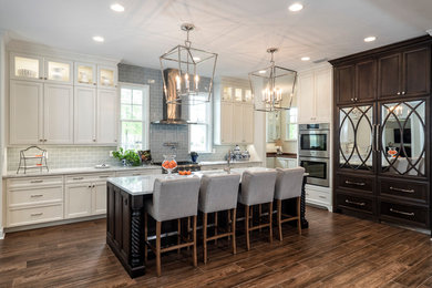 Mid-sized elegant l-shaped dark wood floor open concept kitchen photo in Miami with recessed-panel cabinets, white cabinets, gray backsplash, subway tile backsplash, stainless steel appliances, an island, an undermount sink and marble countertops