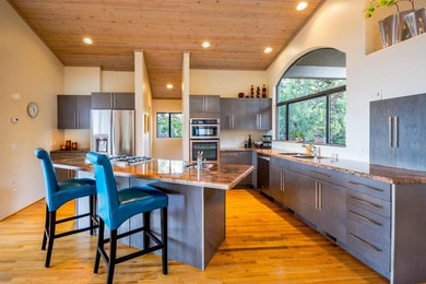 Photo of a large modern l-shaped kitchen/diner in Phoenix with a submerged sink, flat-panel cabinets, dark wood cabinets, granite worktops, stainless steel appliances, medium hardwood flooring, an island and brown floors.