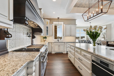 Kitchen - traditional vinyl floor kitchen idea in Other with an undermount sink, raised-panel cabinets, white cabinets, granite countertops, white backsplash, ceramic backsplash, paneled appliances and two islands