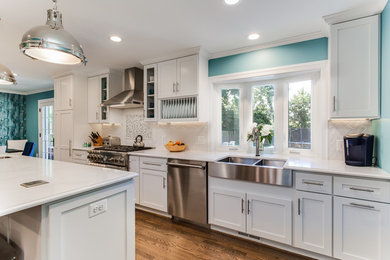 Large transitional galley medium tone wood floor and brown floor eat-in kitchen photo in DC Metro with a farmhouse sink, shaker cabinets, white cabinets, quartz countertops, white backsplash, ceramic backsplash, stainless steel appliances, an island and white countertops