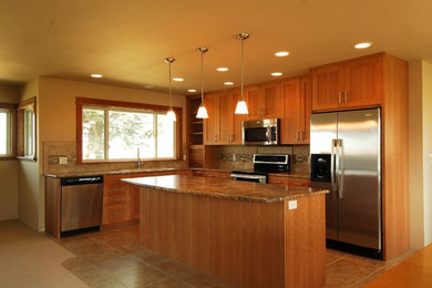Example of a classic l-shaped eat-in kitchen design in Other with a drop-in sink, shaker cabinets, medium tone wood cabinets, granite countertops, brown backsplash, mosaic tile backsplash and stainless steel appliances