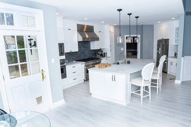 Mid-sized trendy u-shaped light wood floor and gray floor eat-in kitchen photo in Philadelphia with an undermount sink, shaker cabinets, white cabinets, marble countertops, gray backsplash, matchstick tile backsplash, stainless steel appliances and an island