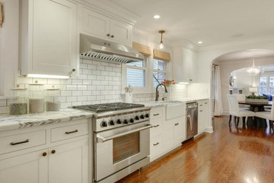 Example of a beach style galley dark wood floor kitchen design in Portland with shaker cabinets, marble countertops, white backsplash and stainless steel appliances