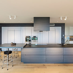 Immagine di una grande cucina minimal con lavello a doppia vasca, ante lisce, ante in legno bruno, elettrodomestici in acciaio inossidabile, parquet chiaro, top in quarzo composito e pavimento beige