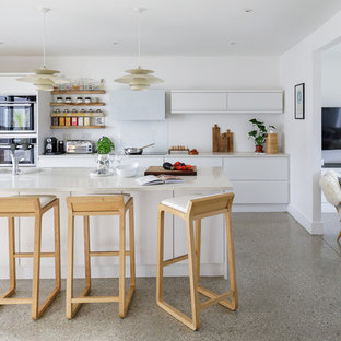 Inspiration for a medium sized contemporary galley kitchen in Cornwall with a double-bowl sink, flat-panel cabinets, white cabinets, white splashback, an island, grey floors, white worktops and stainless steel appliances.